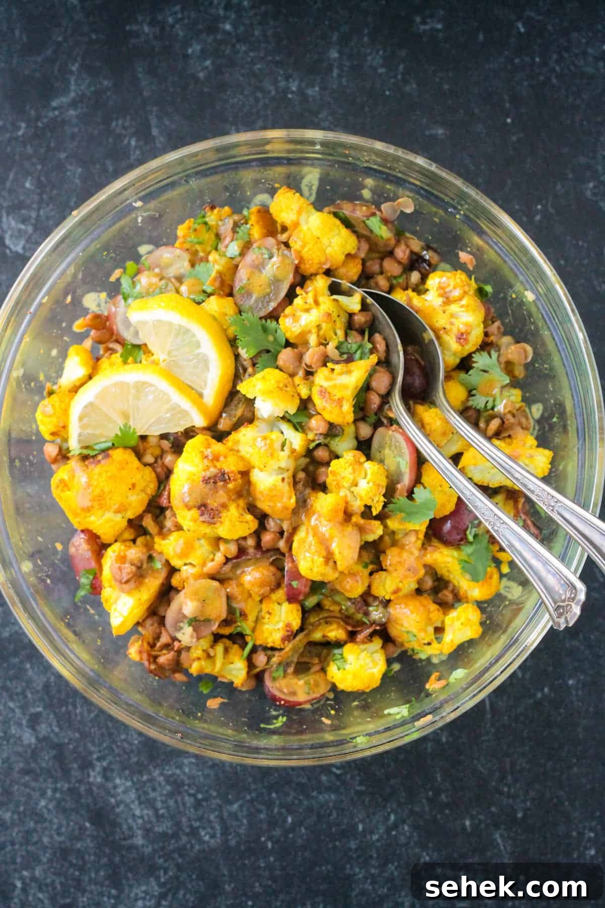 Curry-Roasted Cauliflower Salad with Lemon Tahini Dressing 9 Two spoons in a bowl of curry roasted cauliflower salad.