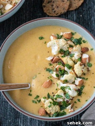 Bowl of creamy vegan cauliflower soup topped with roasted cauliflower and sliced almonds.