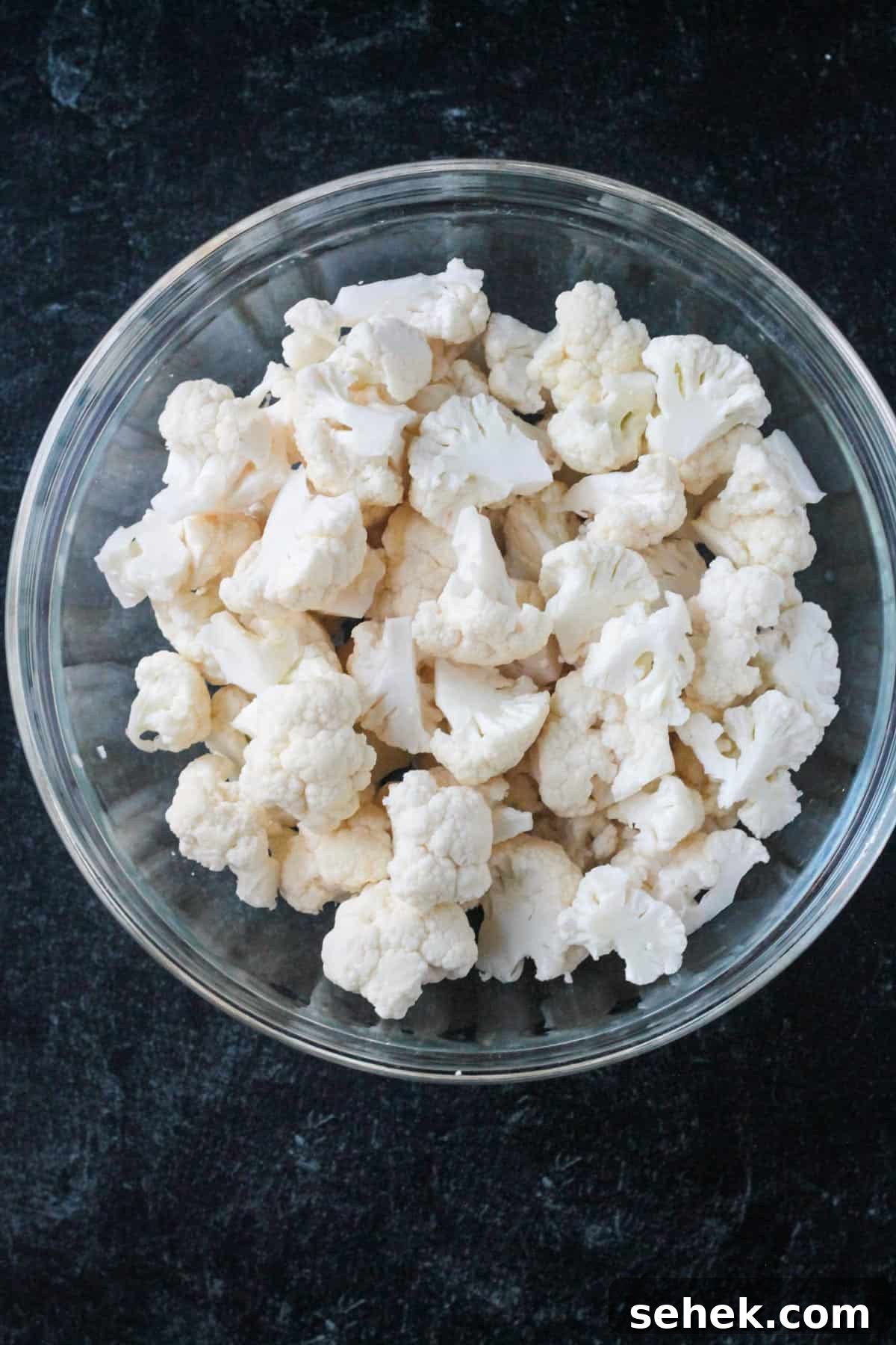Curry-Roasted Cauliflower Salad with Lemon Tahini Dressing 2 Raw cauliflower florets in a mixing bowl.