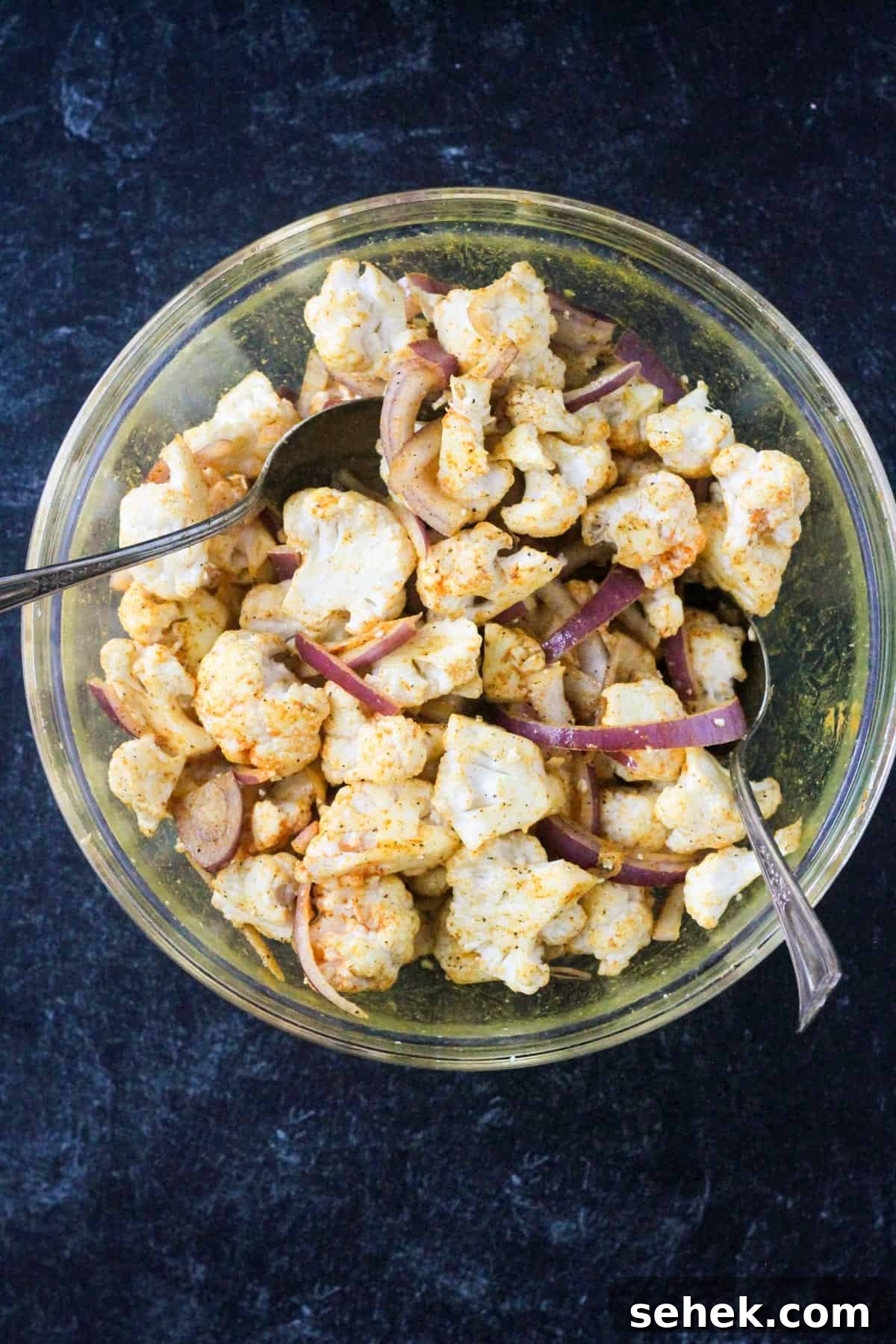 Curry-Roasted Cauliflower Salad with Lemon Tahini Dressing 4 Veggies tossed with spices in a mixing bowl.