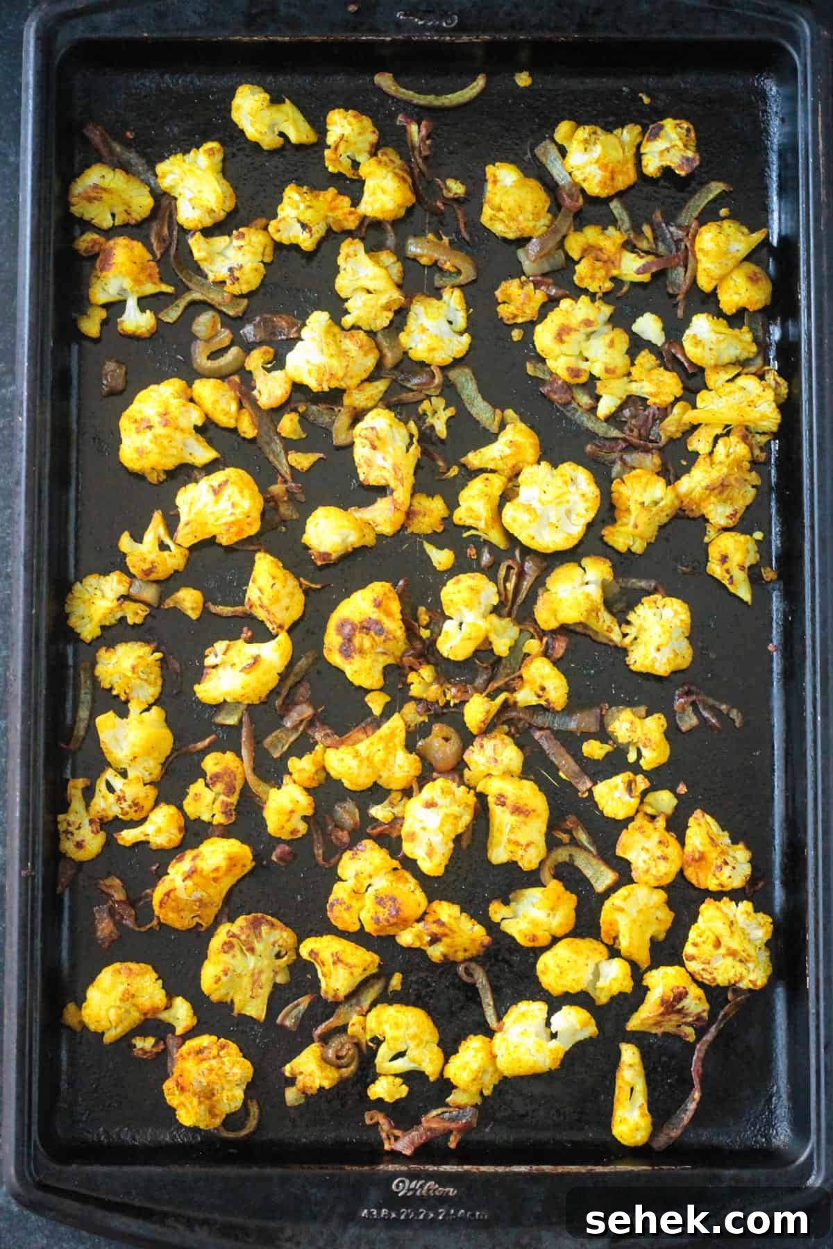 Curry-Roasted Cauliflower Salad with Lemon Tahini Dressing 6 Golden roasted cauliflower on a baking sheet.