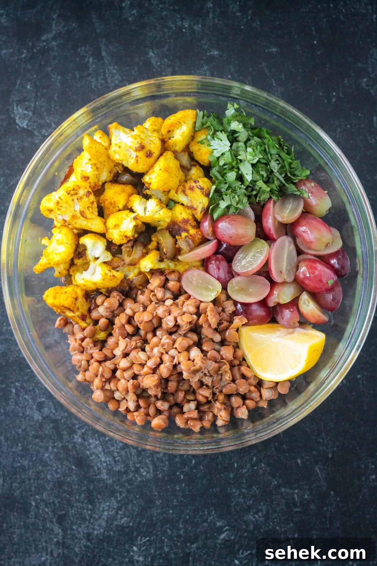 Curry-Roasted Cauliflower Salad with Lemon Tahini Dressing 7 Lentils, roasted cauliflower, halved grapes, and chopped cilantro in a mixing bowl.