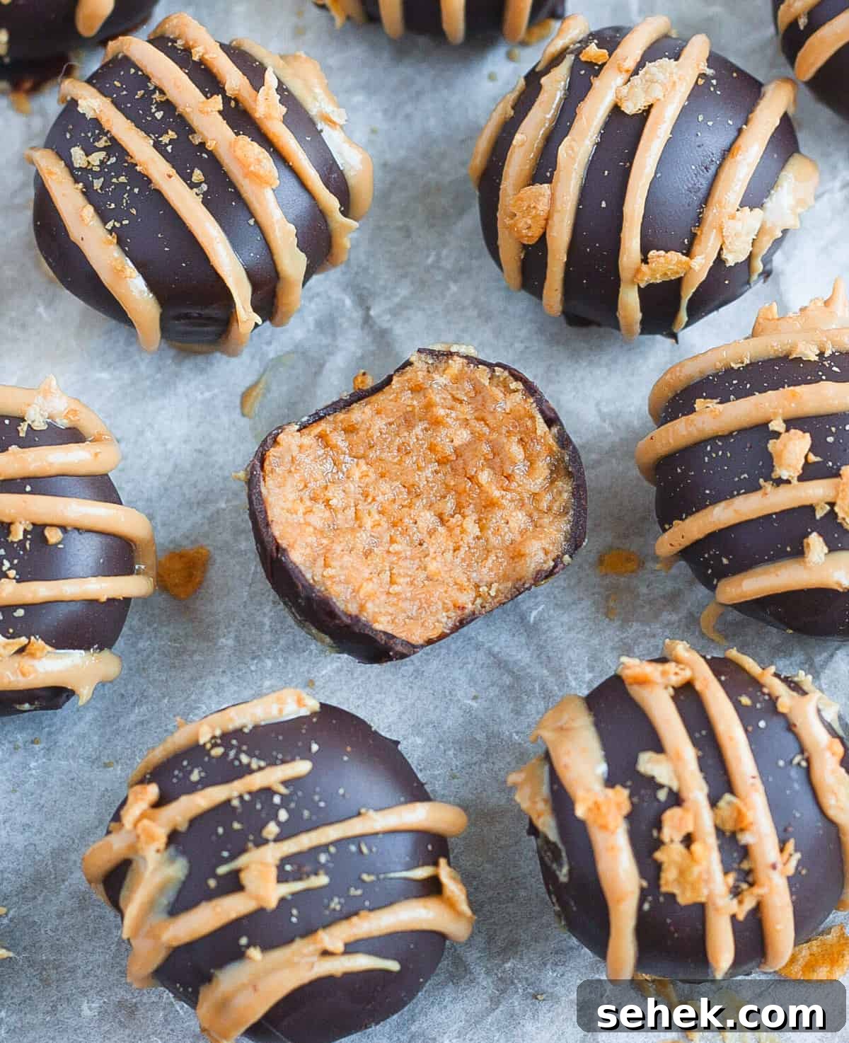No-Bake Chocolate Peanut Butter Balls Recipe That Melts in Your Mouth 4 One truffle with a bite taken off over a sheet of baking paper.