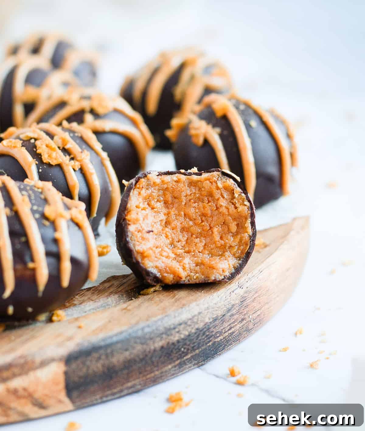 No-Bake Chocolate Peanut Butter Balls Recipe That Melts in Your Mouth 7 One truffle with a bite taken off sitting on a round wooden board.