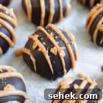 No-Bake Chocolate Peanut Butter Balls Recipe That Melts in Your Mouth 8 Close up on a truffle over a sheet of baking paper.