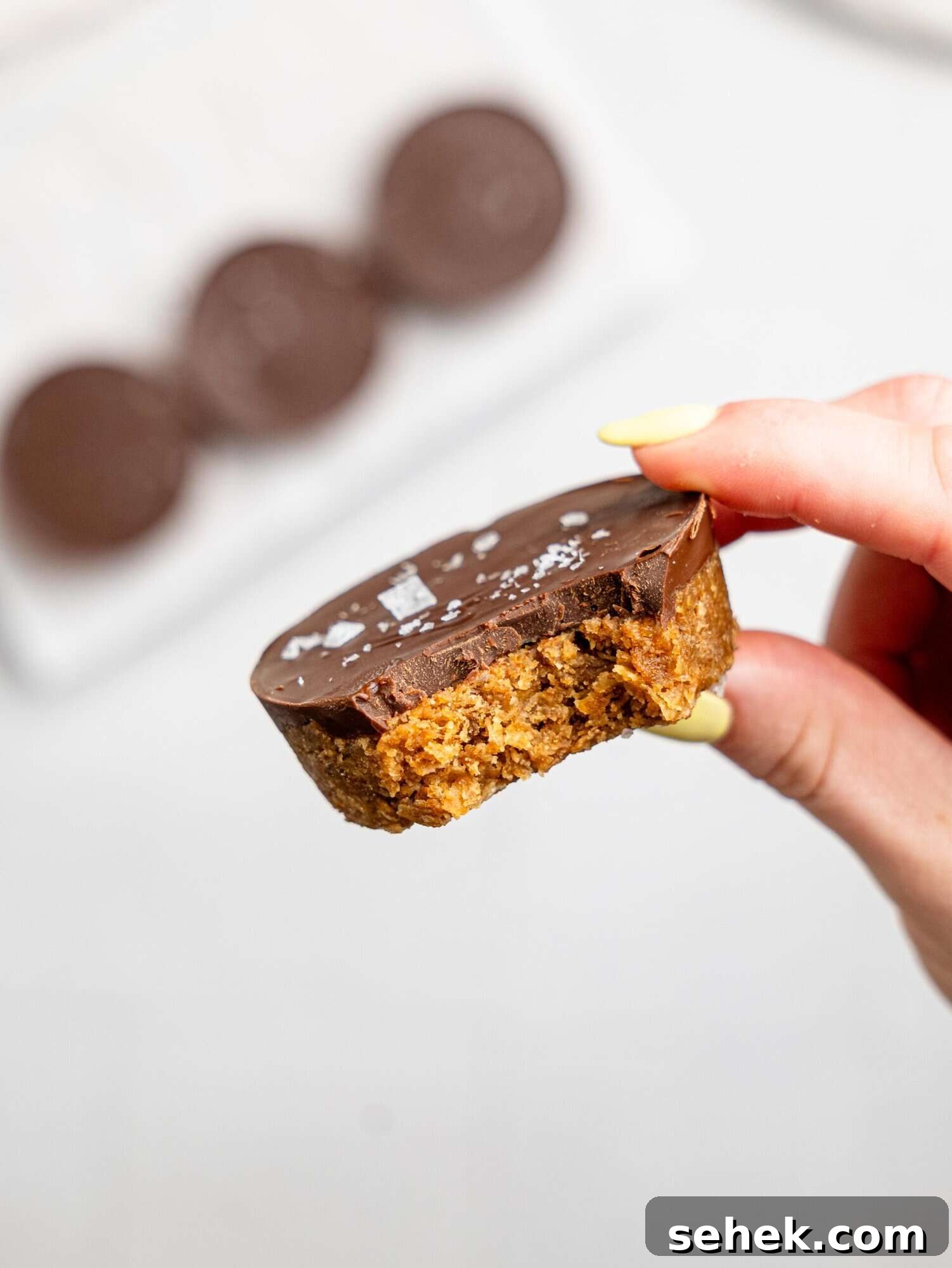 A hand holding a half-eaten peanut butter weetbix cup.