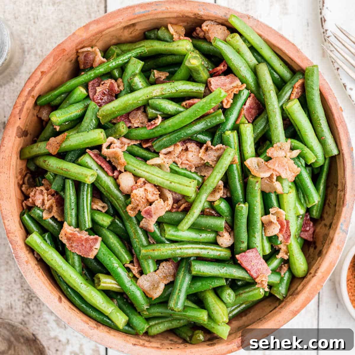 28 Delicious Sides to Serve with Jambalaya 27 close up of a ceramic bowl full of cajun green beans with bacon