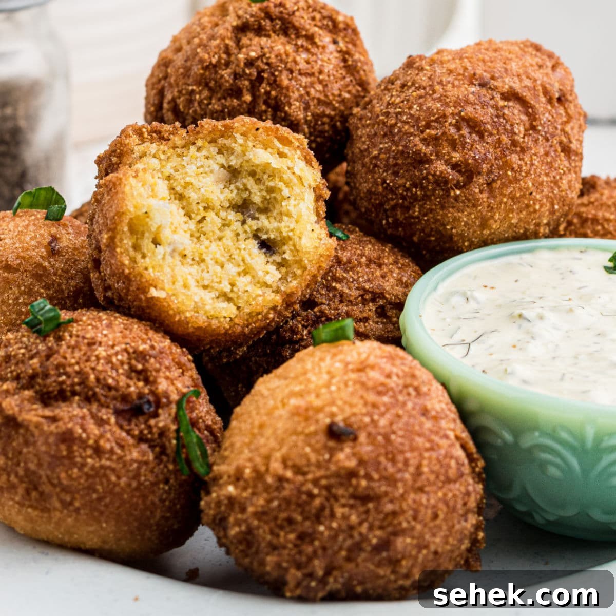 28 Delicious Sides to Serve with Jambalaya 30 Some sweet hush puppies on a plate with a bite taken out of one, with a dip.