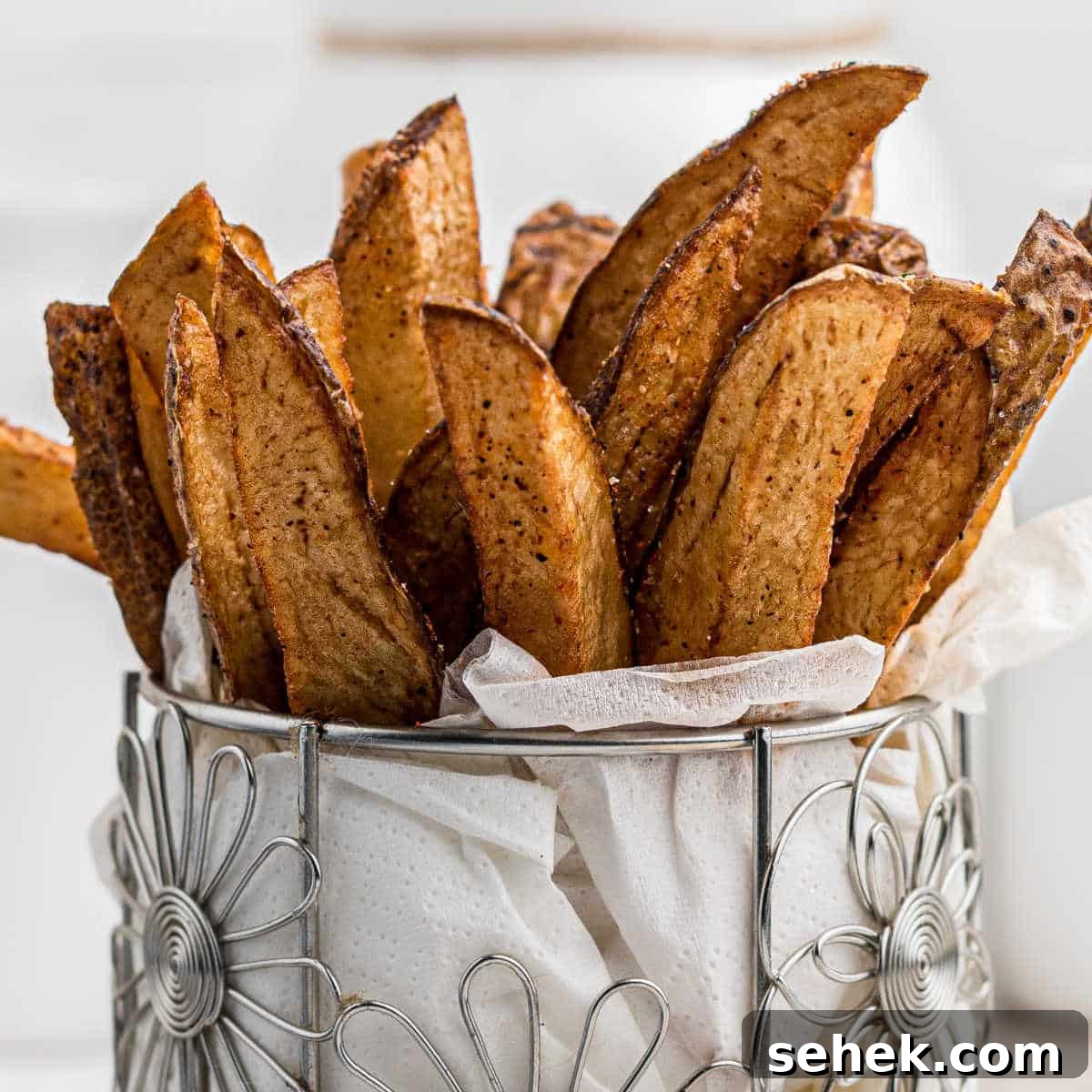 28 Delicious Sides to Serve with Jambalaya 31 a closeup image of some popeyes cajun fries in a cylindrical flower like container with white paper towel