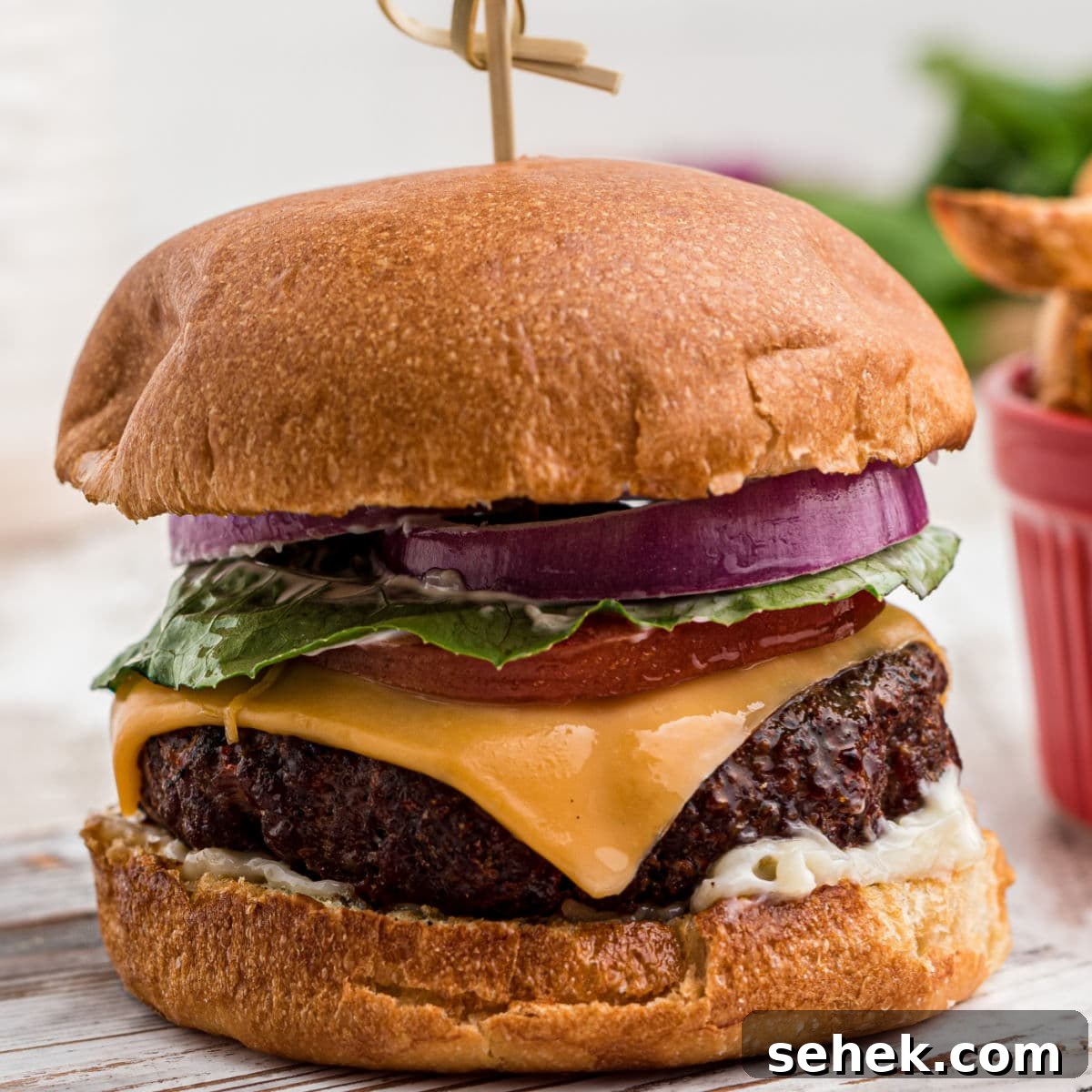 28 Delicious Sides to Serve with Jambalaya 10 close up of a dressed venison burger with a bowl of french fries in the background