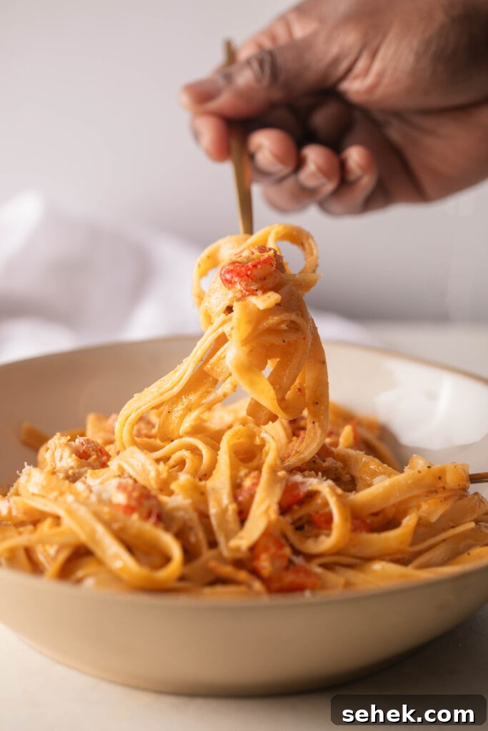 Holding a fork full of Crawfish Fettuccine with a gold fork.
