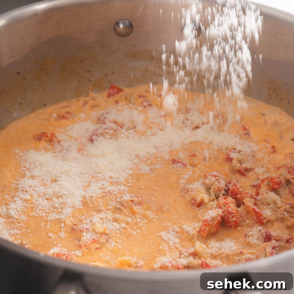 Sprinkling Parmesan cheese into the crawfish Alfredo sauce.