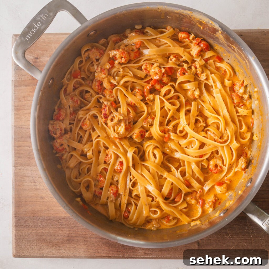 Crawfish Fettuccine Alfredo in a stainless steel sauce pan on cutting board.