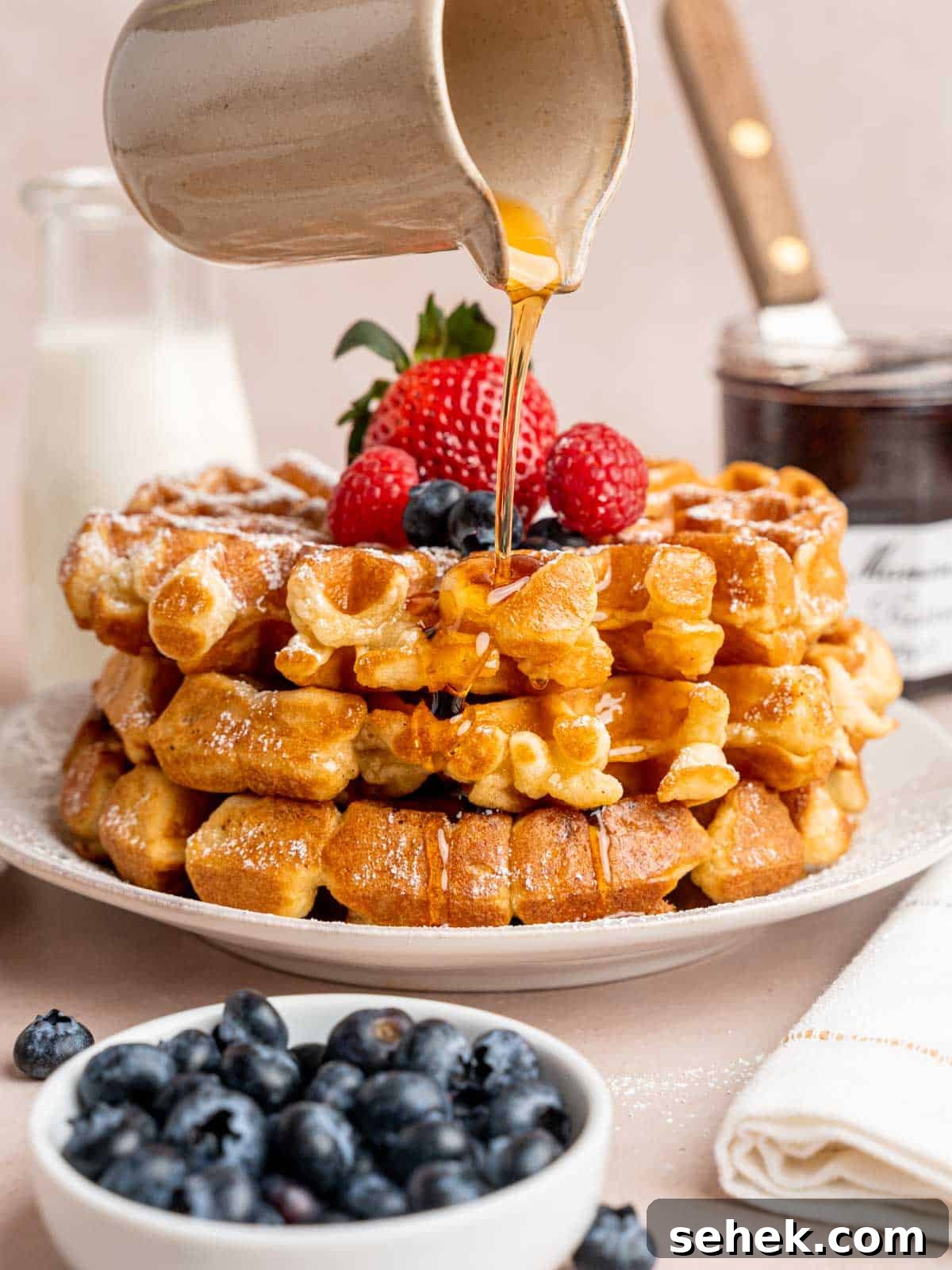 Homemade Belgian Waffles Recipe for Crispy, Fluffy Results 2 Pouring maple syrup on top of a stack of waffles.