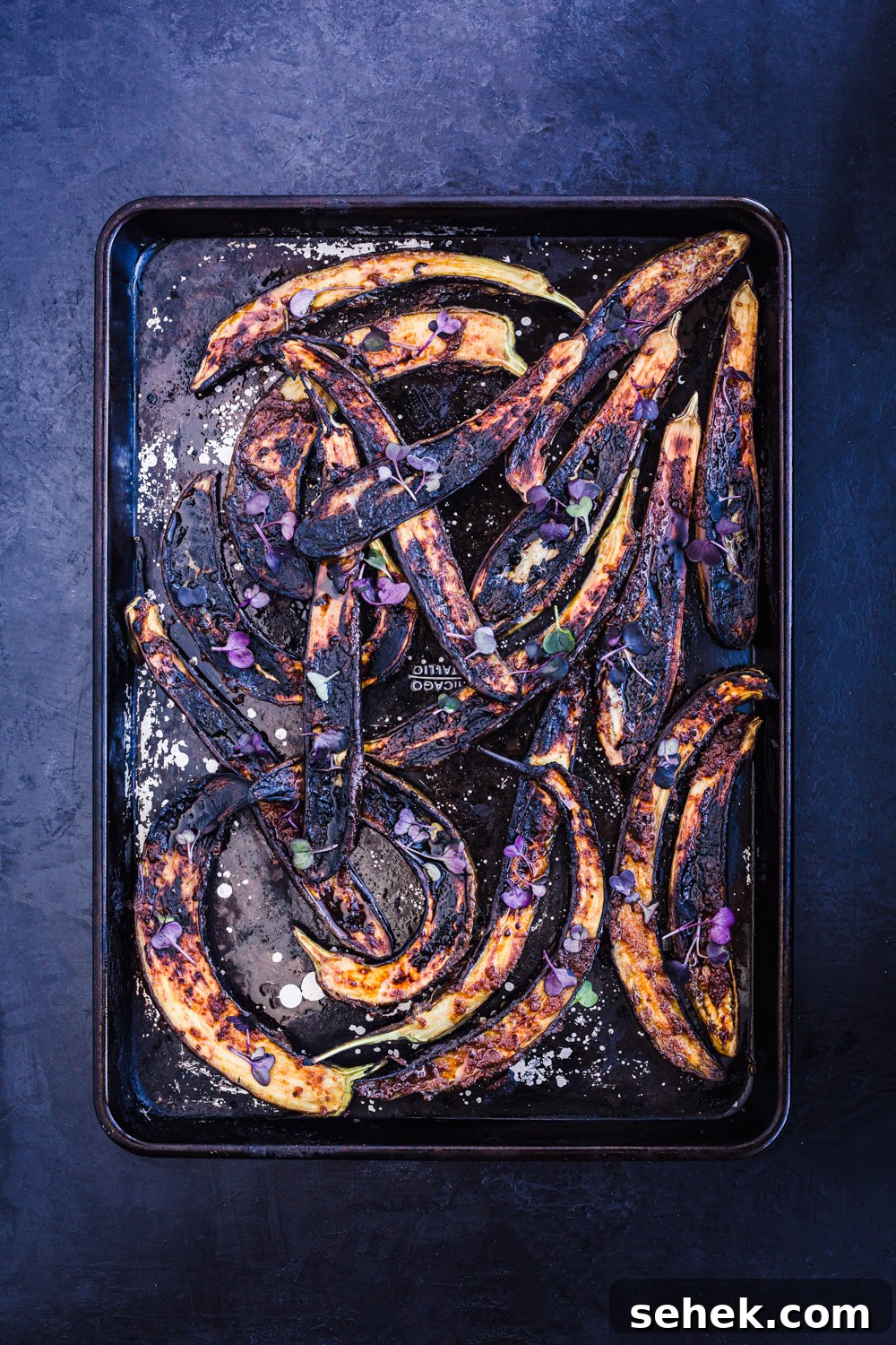 Ginger Miso Glazed Eggplant Recipe for Savory Asian Flavor 3 Ginger-miso glazed eggplant on a baking sheet, just out of the oven and topped with micro greens and flaky sea salt.