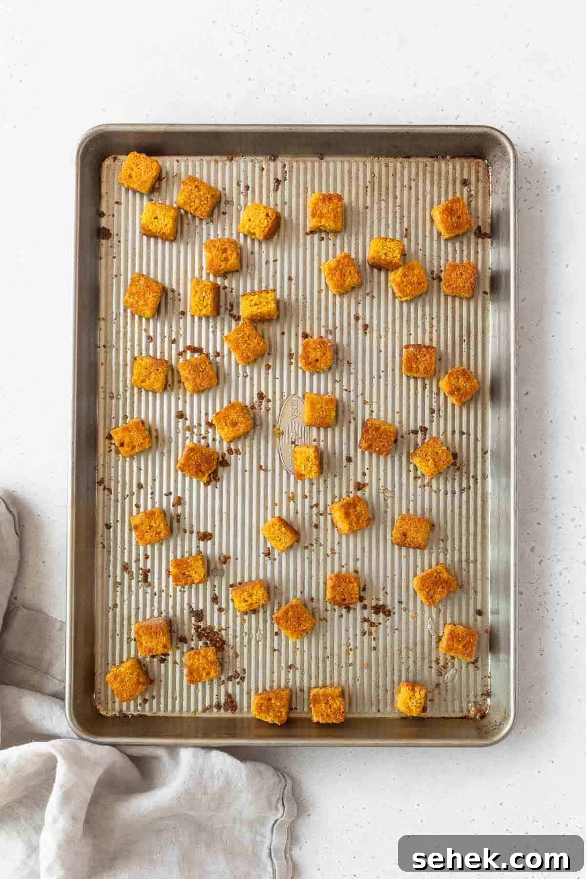 Crispy Cornbread Croutons for Salads and Soups 14 Toasted cornbread croutons on a baking sheet.