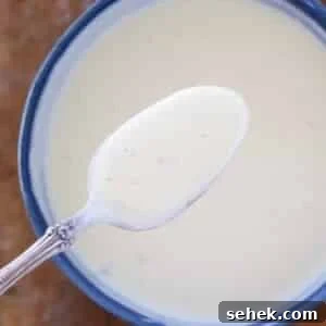 Classic Vanilla Crème Anglaise: French Custard Sauce 7 creme anglaise on spoon over bowl.