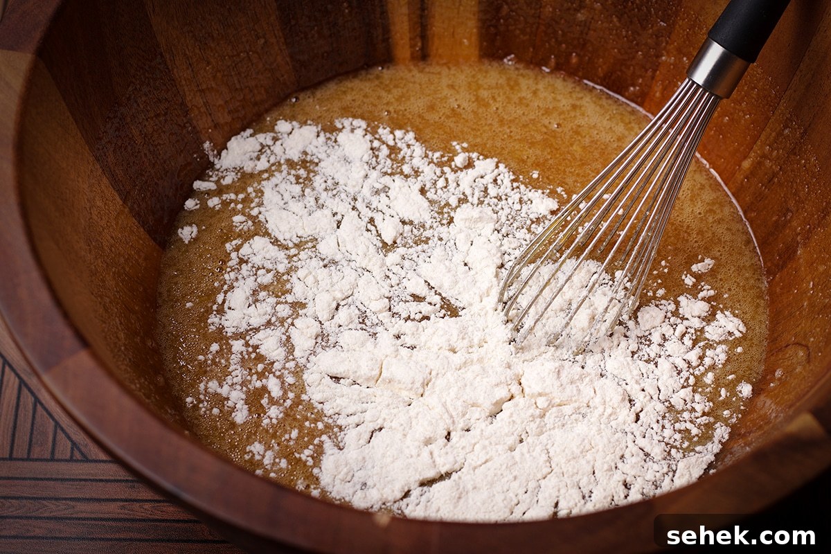 Someone using a wire whisk to mix flour into the rest of the pecan pie filling ingredients.