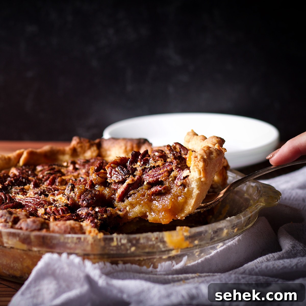 Someone using a pie server to serve a slice of pecan pie.