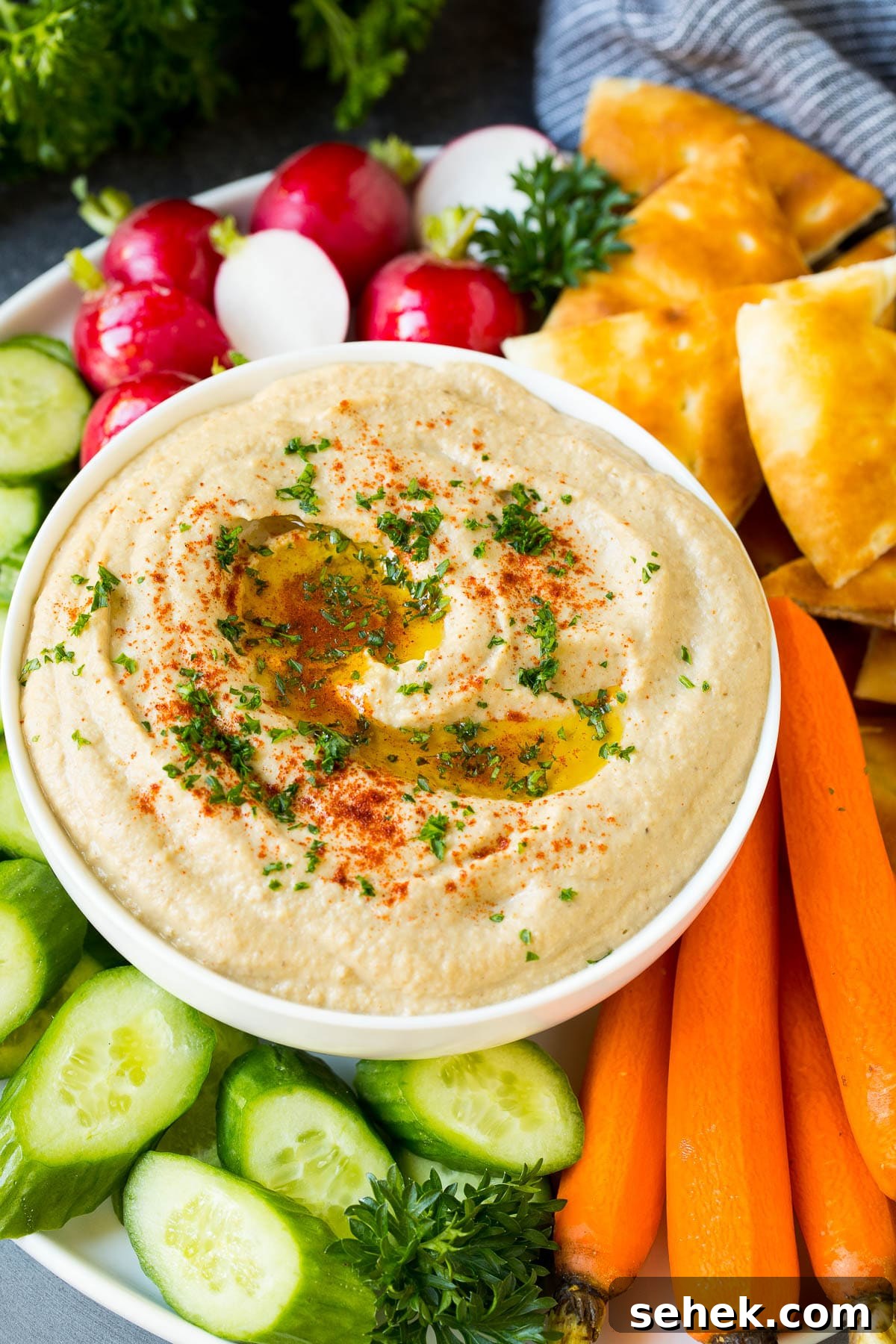 Smoky Baba Ganoush: Creamy Roasted Eggplant Dip 5 Baba ganoush in a bowl surrounded by bread and vegetables.