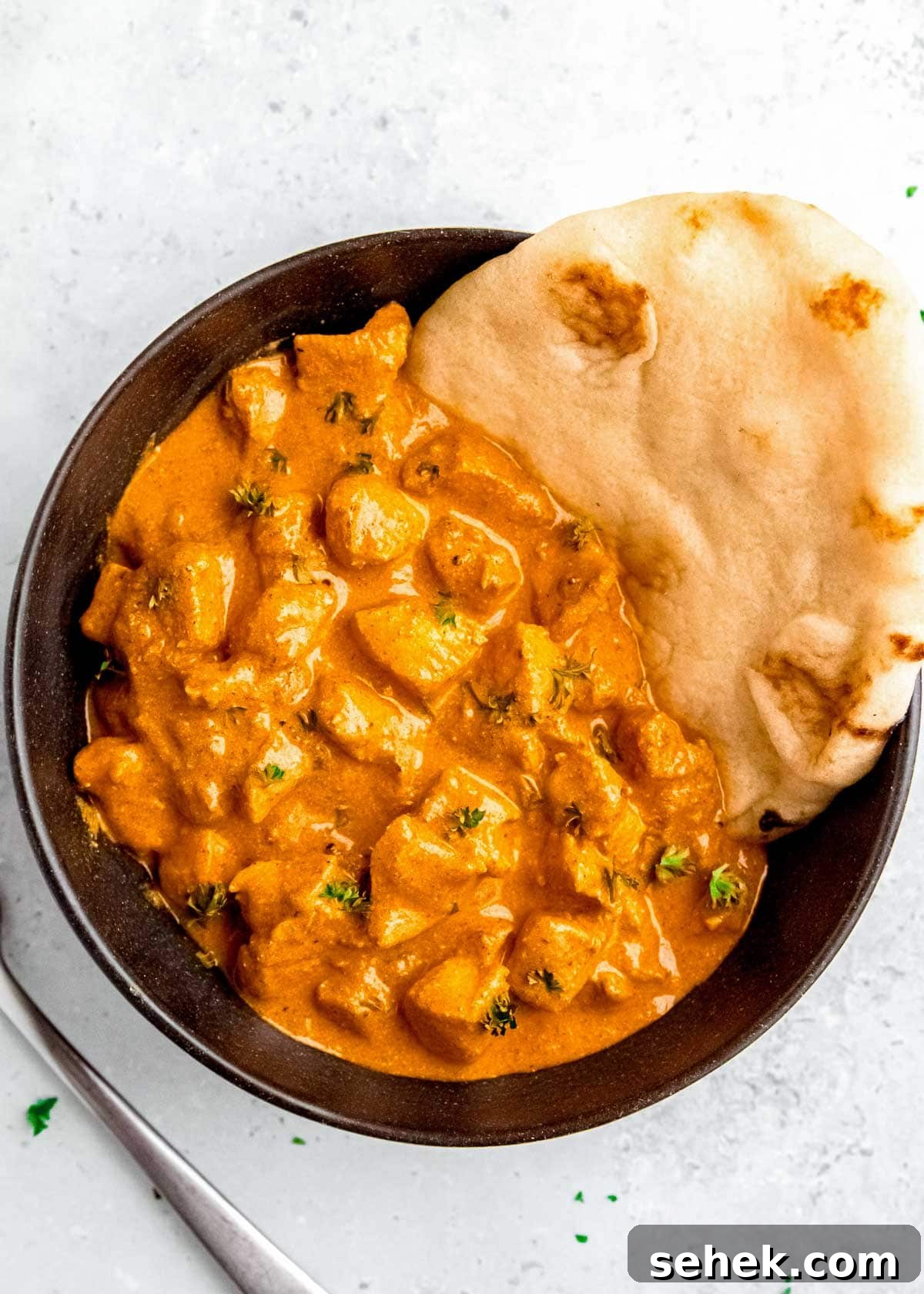 Creamy Indian Butter Chicken Recipe 3 overhead shot showing a black bowl full of creamy butter chicken with a side of naan bread