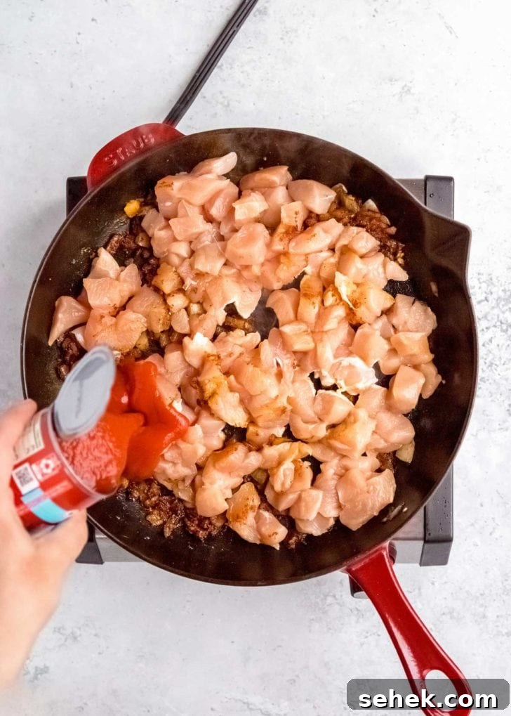 Creamy Indian Butter Chicken Recipe 8 raw chicken being added to skillet with other butter chicken ingredients