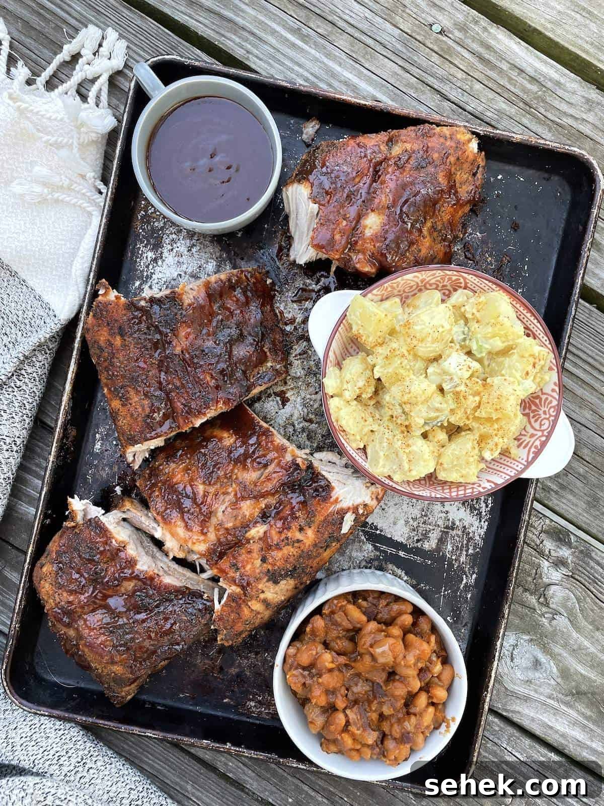 Classic Southern Potato Salad Recipe 9 A tray with baked beans from scratch, baby back ribs, and southern potato salad.