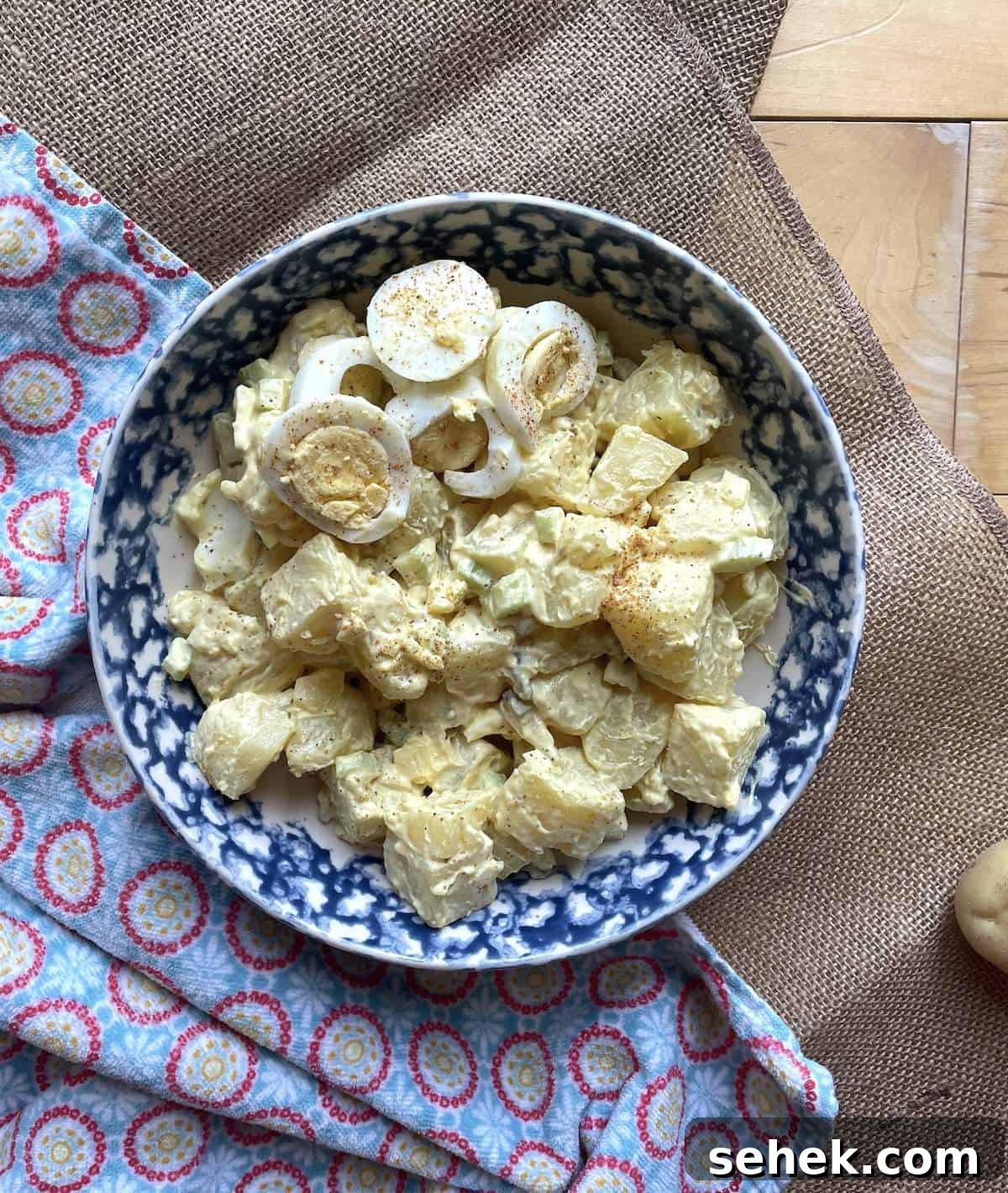 Classic Southern Potato Salad Recipe 10 A bowl of homemade potato salad with pickles and celery topped with hard-boiled eggs.