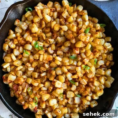Classic Southern Potato Salad Recipe 11 A close-up of blackened, sautéed corn kernels garnished with fresh green onions, served in a cast iron skillet.