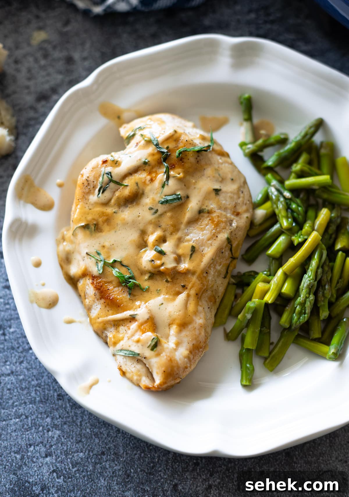 Skillet Chicken with Creamy Mustard Sauce 14 Piece of chicken on a plate topped with mustard cream sauce and asparagus.