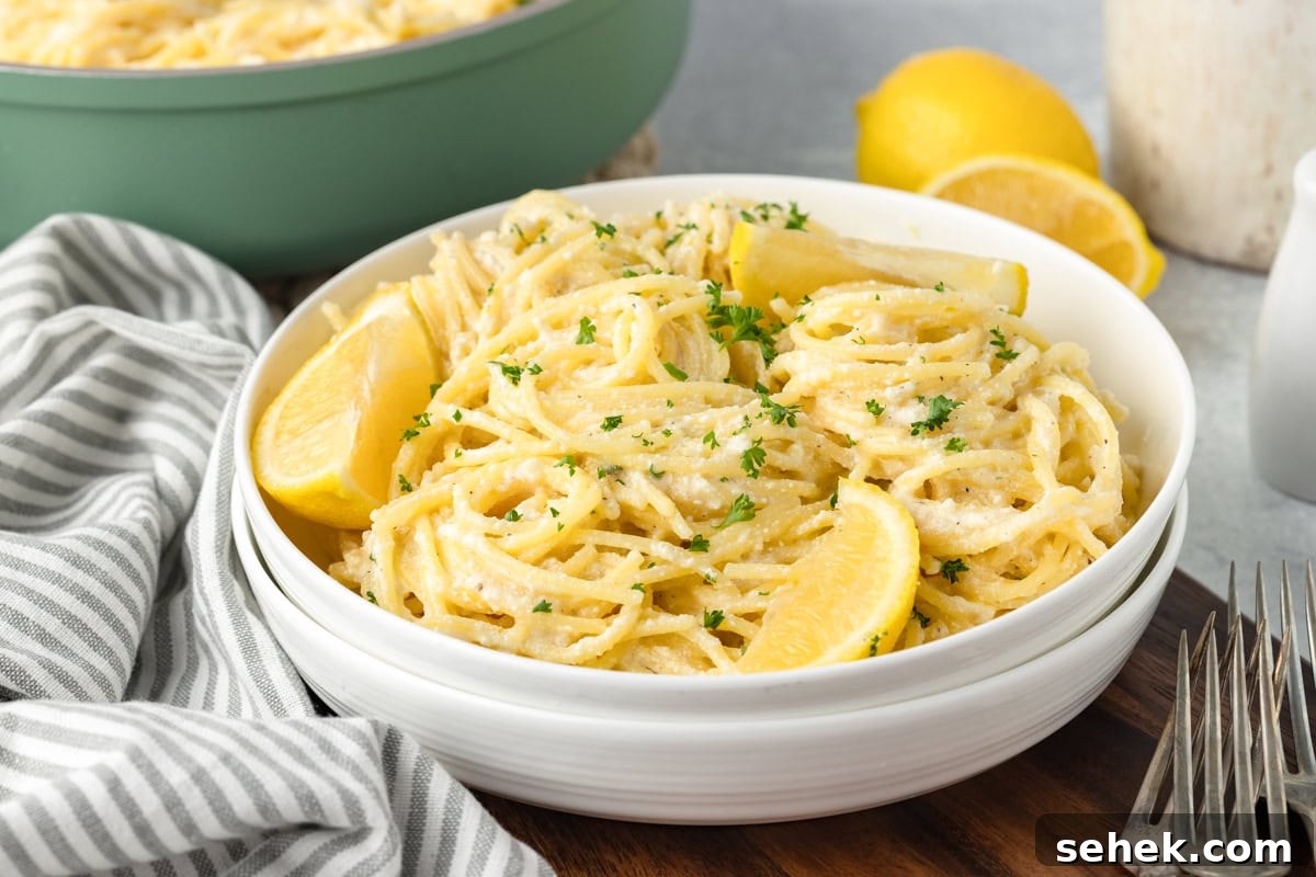 Creamy Lemon Ricotta Pasta with Garlic and Parmesan 6 A dish of creamy spaghetti garnished with lemon wedges and parsley is served in a white bowl.