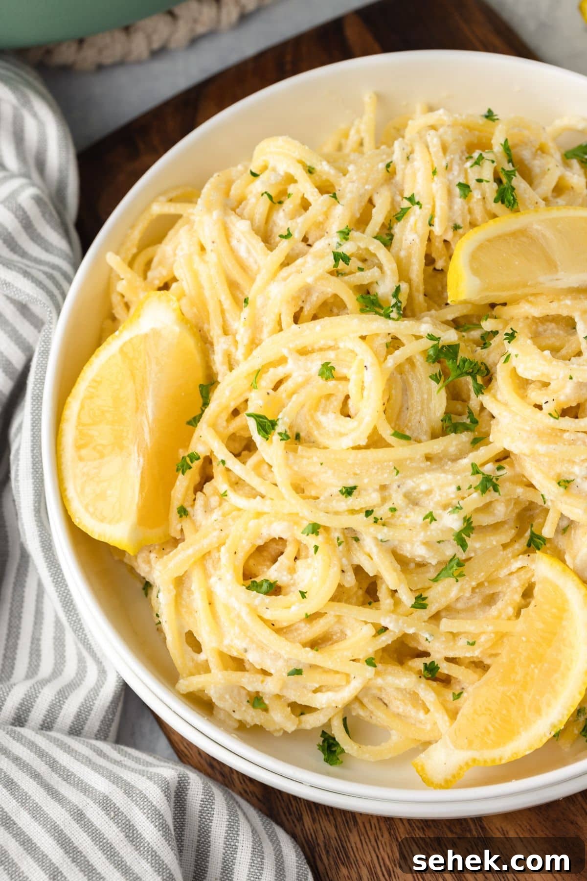 Creamy Lemon Ricotta Pasta with Garlic and Parmesan 7 A bowl of creamy pasta topped with chopped parsley and garnished with lemon wedges.
